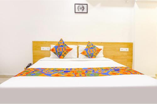 Cama blanca grande con sábanas y almohadas coloridas en FabHotel Saffron Inn I en Pune