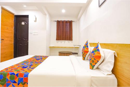 a bedroom with a large white bed with colorful pillows at FabHotel Saffron Inn I - Nr Darshan Museum in Pune
