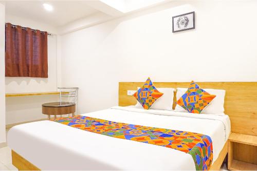 1 dormitorio con 1 cama grande y almohadas coloridas en FabHotel Saffron Inn I en Pune