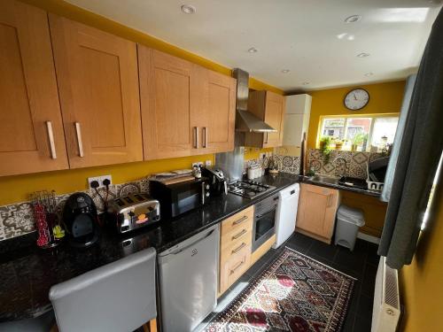 uma cozinha com armários de madeira e um balcão preto em Cosy 2BR House Close to Burton-on-Trent Centre em Burton upon Trent