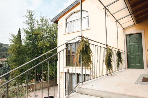 ヴェローナにあるCasale Manzoniの緑のドアとバルコニー付きの家