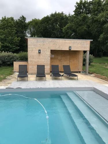 un groupe de chaises assises à côté d'une piscine dans l'établissement Gîte 11 personnes en pleine campagne, à Sainte-Anne-sur-Vilaine