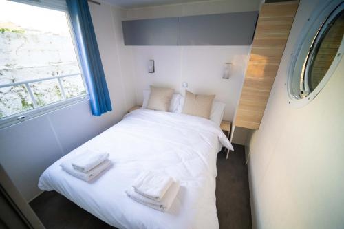 Un pequeño dormitorio con una cama blanca con toallas. en Alojamiento - Bungalows en el centro de Laredo a 200 m de la playa en Laredo