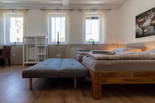 2 camas en una habitación con ventanas y reposapiés en Apartment 4you, en Oberpullendorf