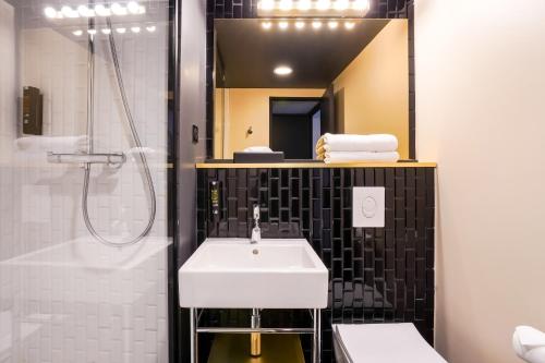 a bathroom with a sink and a shower and a mirror at Kyriad - Créteil - Bonneuil-sur-Marne in Bonneuil-sur-Marne