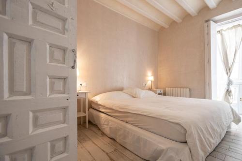 Habitación blanca con cama y ventana en Plaza San Antonio, Casa Bugambilla, en Cádiz