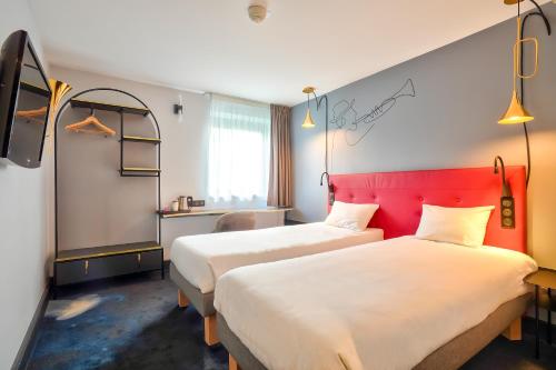 um quarto de hotel com duas camas e uma cabeceira vermelha em Kyriad - Créteil - Bonneuil-sur-Marne em Bonneuil-sur-Marne
