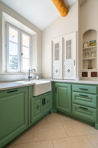 une cuisine avec des armoires vertes et un évier dans l'établissement La Bastide Des As, à Gordes