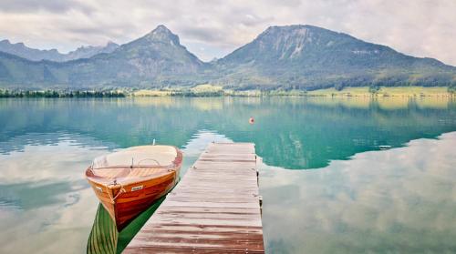 a boat is docked at a dock on a lake at TAUROA Landhaus zu Appesbach in St. Wolfgang