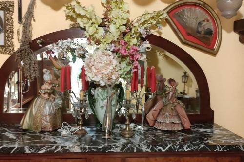 a table with a vase of flowers and figurines on it at Apartament volcà Rocanegra in Santa Pau
