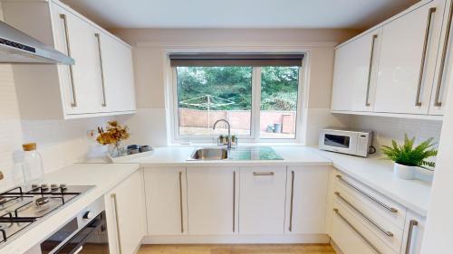 een witte keuken met een wastafel en een raam bij Inviting Apt near the Valley Park in Exeter