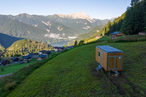 une petite maison assise sur une colline dans un champ dans l'établissement Una stanza panoramica a Sauris - Friland, à Sauris