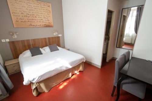 a bedroom with a white bed and a desk and a mirror at Hotel Chalet De L'isere in Cannes