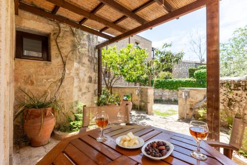 a wooden table with two glasses of wine on a patio at Kalimera Archanes Village in Archanes