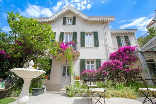 une maison blanche avec des fleurs roses et une fontaine dans l'établissement Hotel Chalet De L'isere, à Cannes