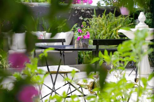a table and chairs in a garden with flowers on it at Hotel Chalet De L'isere in Cannes