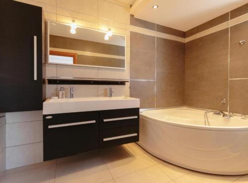 een badkamer met een bad, een wastafel en een spiegel bij M & B in Bibinje