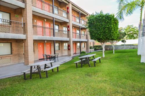 a park with benches and tables in front of a building at Hotel Colonial Hermosillo in Hermosillo