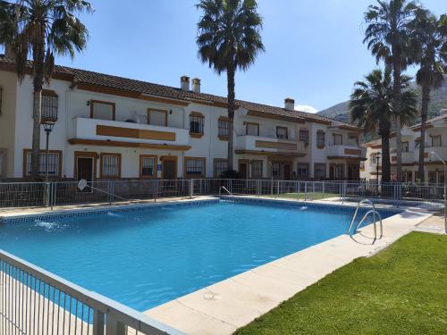 una piscina frente a un edificio con palmeras en La Escapadita, en Benaoján