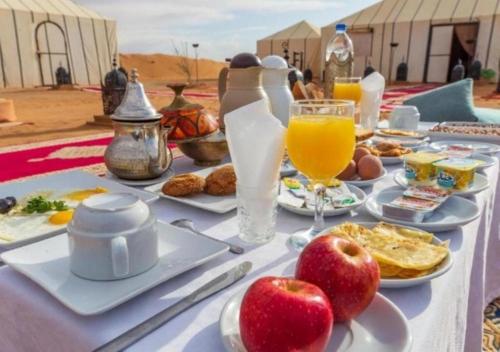 a table with breakfast foods and drinks on it at Sunset Camp Merzouga in Merzouga