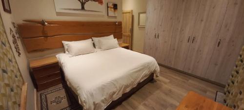 a bedroom with a large bed with white sheets at Golf and Relaxation at Kingswood Golf Estate in George