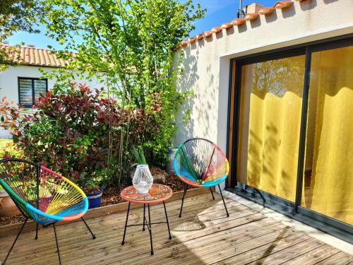 three chairs and a table on a wooden deck at Les Iris in Les Herbiers
