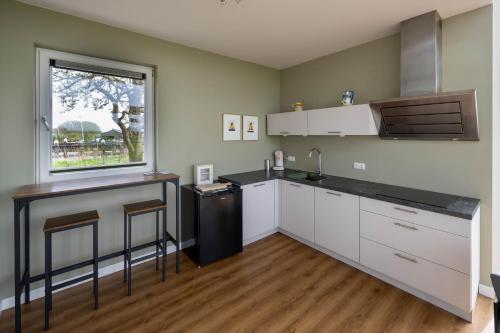 a kitchen with white cabinets and a window at Aan de Amstel in De Kwakel