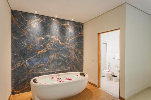 y baño con bañera y pared de mármol. en Anacã Ecolounge, en Bonito