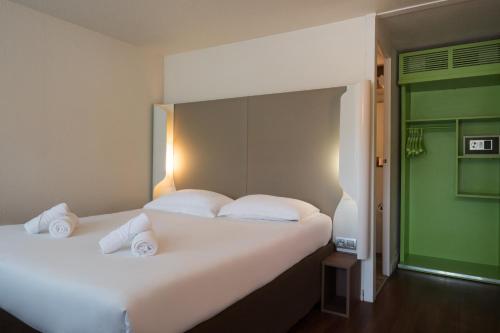 a bedroom with a large white bed with a green door at The Originals Access, Hôtel Foix in Foix