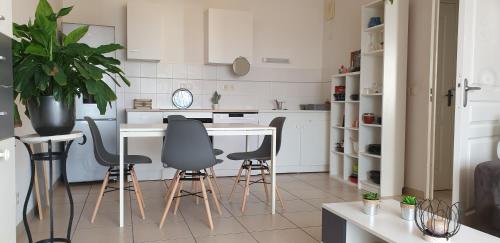 uma cozinha com armários brancos e uma mesa e cadeiras em Appartement T2 à 10 min de Montpellier em Vendargues