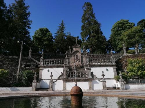 a fountain in front of a building with trees at Casinha Pôr do Sol in Aldeia das Dez