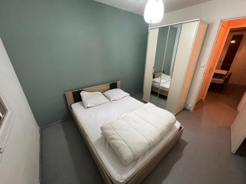 Cette petite chambre comprend un lit avec des draps blancs et un miroir. dans l'établissement Le Palalda, à Amélie-les-Bains-Palalda