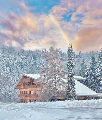 a rainbow in the sky above a house in the snow at Hôtel Chalet Frère Joseph in Ventron