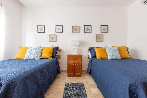 two beds in a room with blue and yellow pillows at Apartamento en Residencial Jardines de Monserrat in Las Terrenas