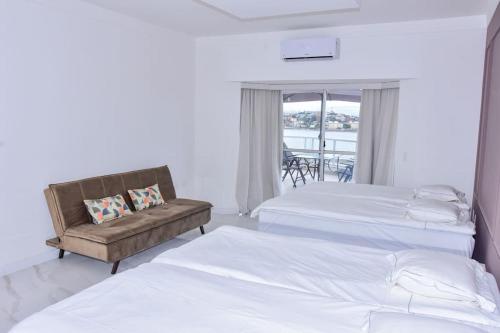um quarto de hotel com duas camas e um sofá em Casa Oásis do Moreno 6 em Vila Velha