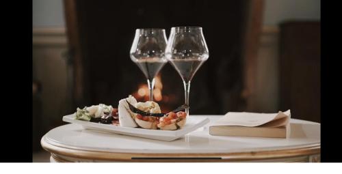 RodigoにあるVilla dei Tigli 920 Liberty Resortのシャンパン2杯、テーブルの上に盛り付けられたお皿