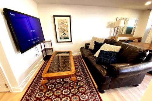 sala de estar con sofá de cuero y TV en Stylish Deluxe 2BDR Guest Apartment, en Hamilton