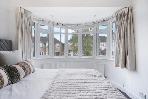 a white bedroom with a bed and windows at Hububb Luxury Eastcote in Eastcote