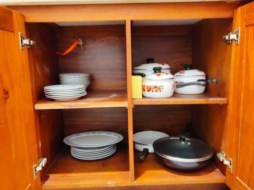 a wooden cabinet with plates and dishes in it at A two bedroom luxury apartment at Canterbury Golf Resort in Kahatuduwa