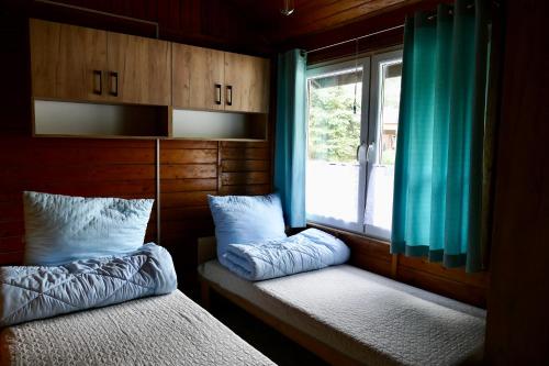 トゥラバにあるDomek typu Mikołajki na Ośrodku Wędkarko-Turystycznym Rybaczówkaのベッドルーム1室(ベッド2台、青いカーテン付きの窓付)