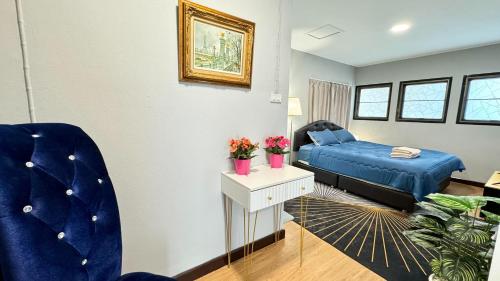 Un dormitorio con una cama azul y una mesa con flores en FRIENDS@SaiLom en Bangkok