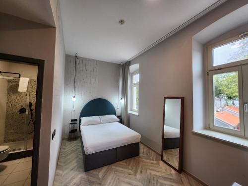 Habitación pequeña con cama y espejo. en Hotel Amfiteatar, en Pula