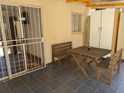 einen Holztisch und Stühle auf einer Terrasse mit einem Tisch und einer Bank in der Unterkunft Home Sweet Home in Polokwane