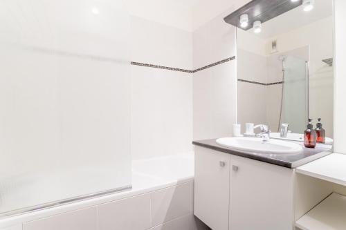 une salle de bain blanche avec un lavabo et un miroir dans l'établissement Appartement Cosy - Vieux lille, à Lille