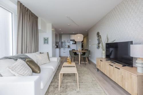 a living room with a white couch and a tv at Haya Seaview - The Pier in Scheveningen