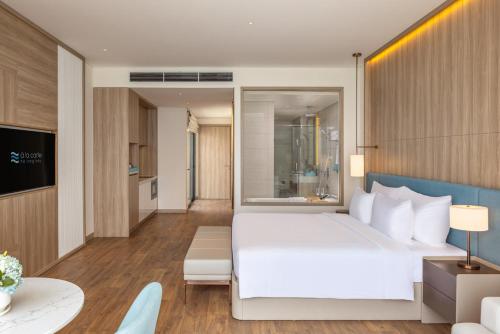 a bedroom with a white bed and a living room at À La Carte Halong Bay in Ha Long