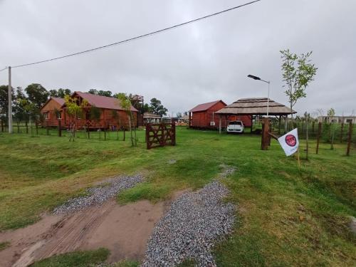 a field with two red buildings and a flag at SanDo Uribe Cabañas Exclusivas solo adultos in Uribelarrea