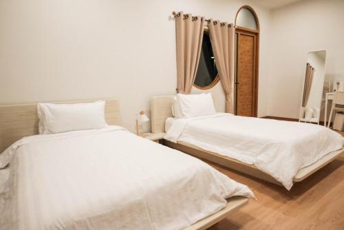 two white beds in a room with a mirror at Wantanee Ville วันทนีย์วิลล์ in Ban Wang Sai