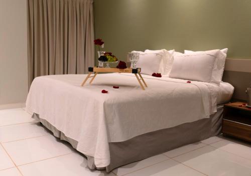 a bed with a table on it with roses on it at Nord Luxxor Juazeiro do Norte in Juazeiro do Norte
