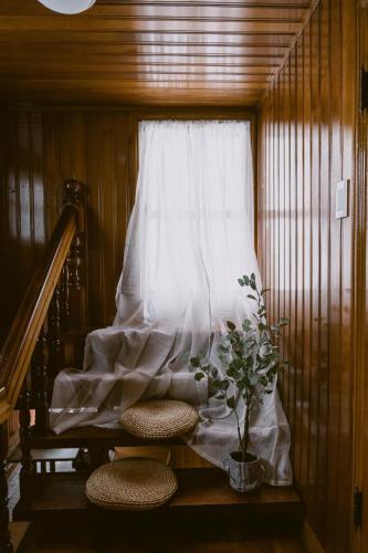 a window with a curtain and two stools and a plant at We are now here in Busan